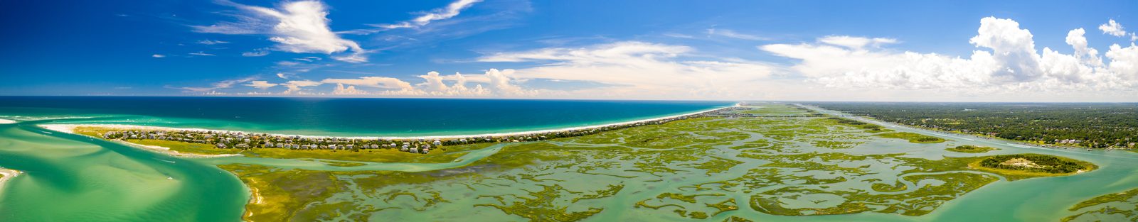 Aerial view of a pristine coastal landscape with turquoise waters, sandy beaches, and expansive wetlands.